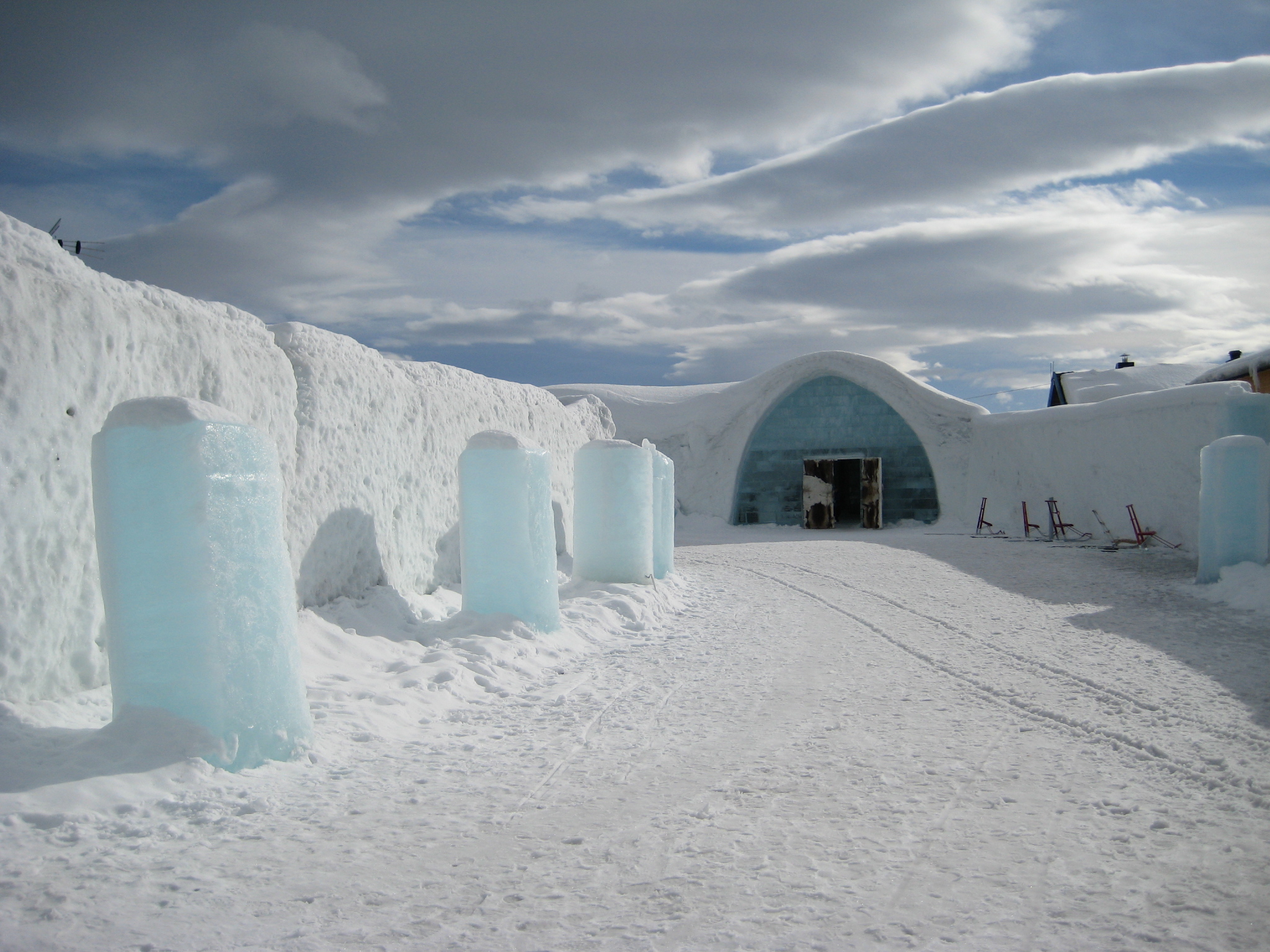 The snow and ice entrance to Icehotel with ice columns and sledges outside.
