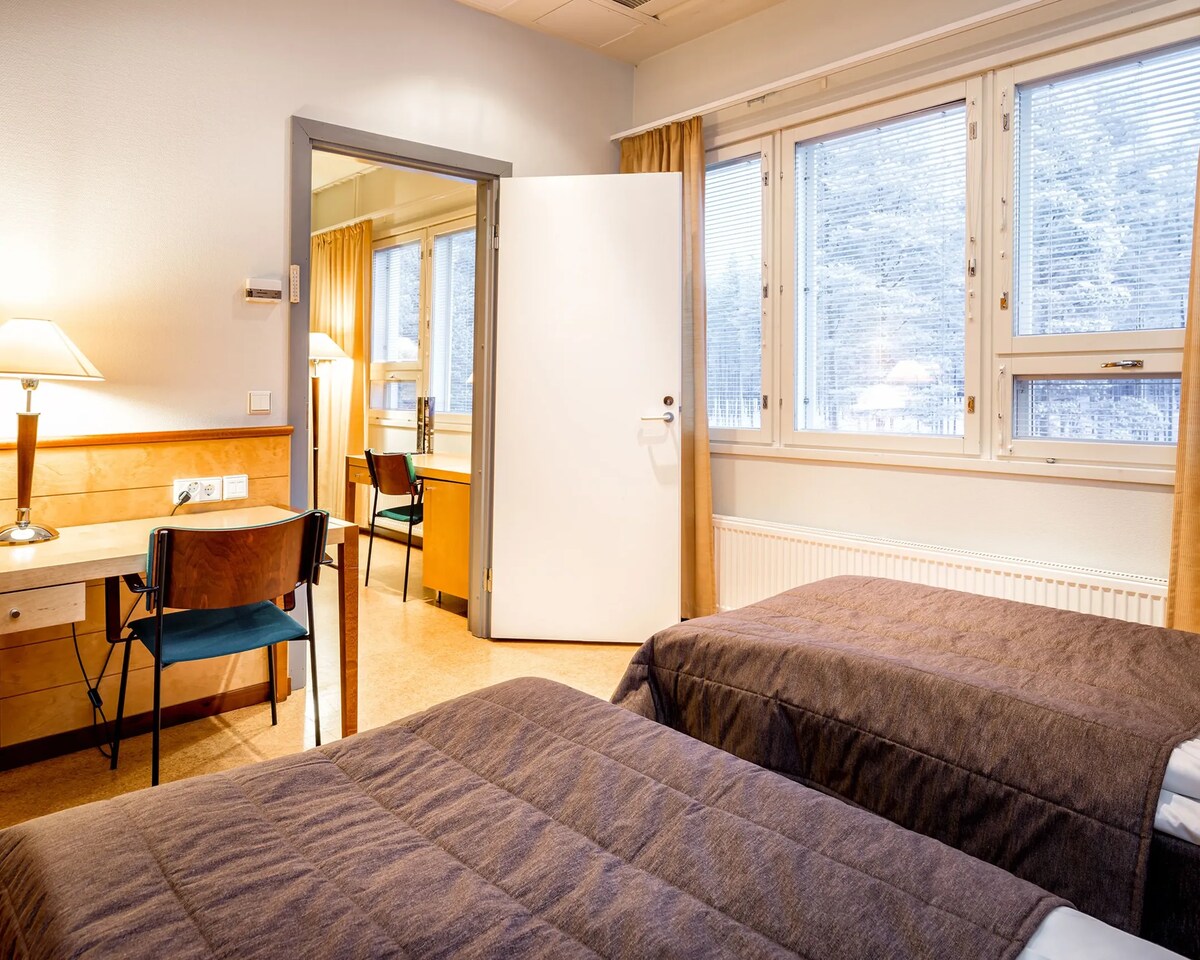 Twin beds and a doorway between rooms in a family room at Rokua Health & Spa.