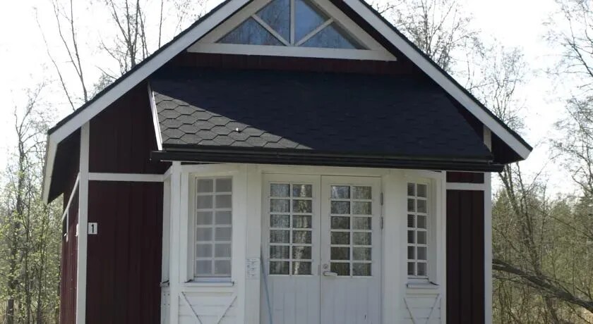 Red wooden cottage with a white entrance porch at Villa Elba in Kokkola